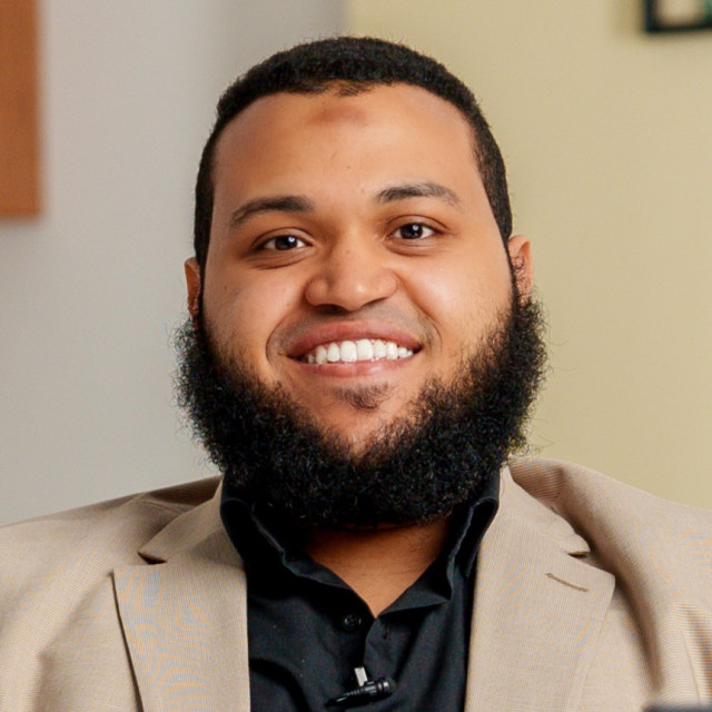 Abu Bakr Mukhtar, English teacher and language coach, smiling at his desk